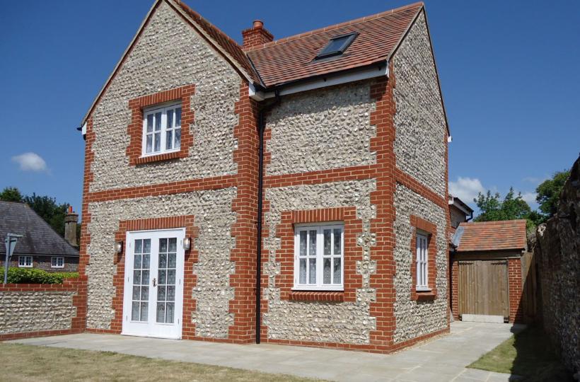 Two storey detached dwelling with brick quoins and flint infill